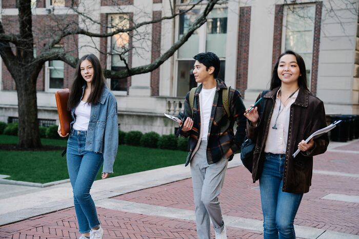 A group of students walking near campus buildings, representing unethical life pro tips for university life.