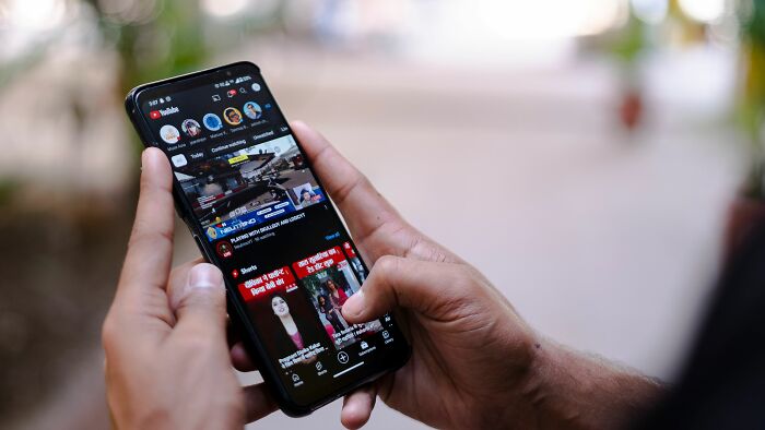 A hand holding a smartphone scrolling through unethical life pro tips on a video app