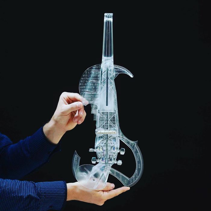 Hands holding a transparent violin created with a 3D printer