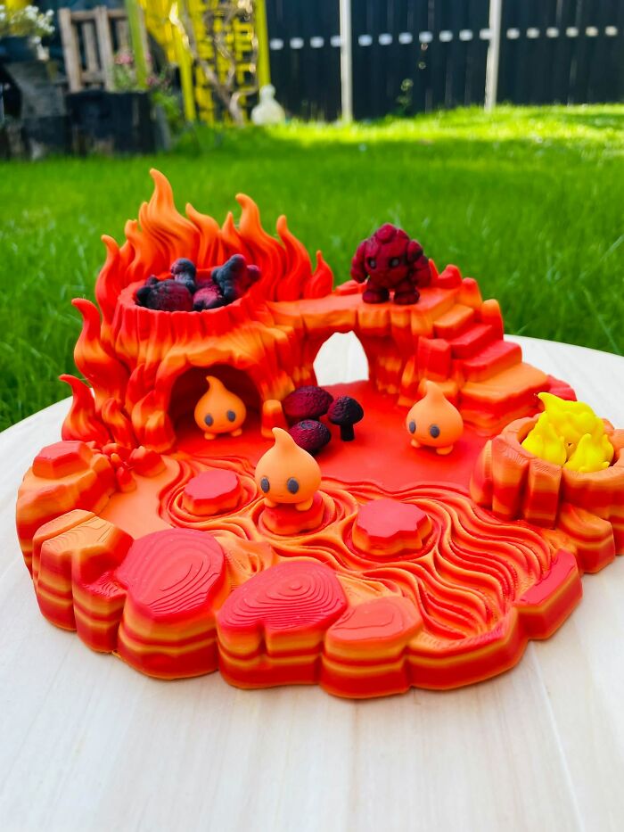 A vibrant 3D printer volcano island playset featuring lava pools and little fire creatures.