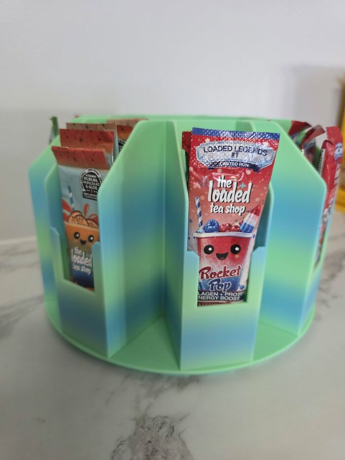 A rotating green and blue 3D printer carousel holding tea flavor packets.