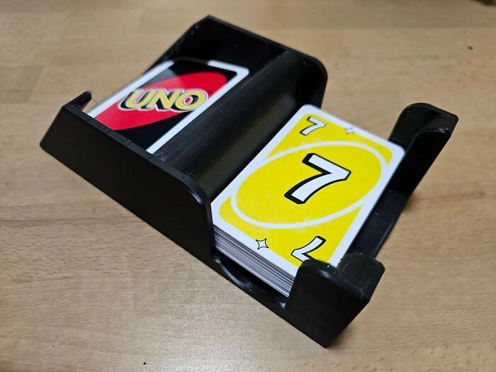 A black 3D printer card holder keeping Uno cards organized on a table.