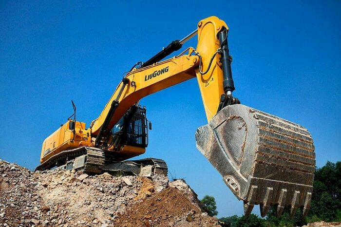 Yellow excavator digging construction site under clear sky representing scary machine hazards