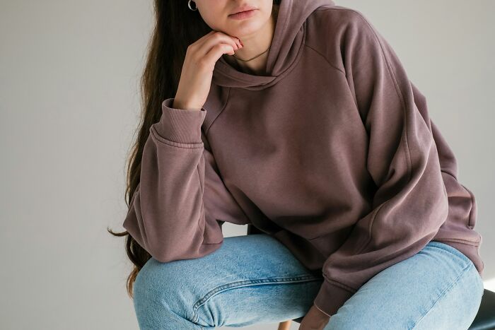 A thoughtful young person sitting in a hoodie, illustrating personal stress during intense family feuds