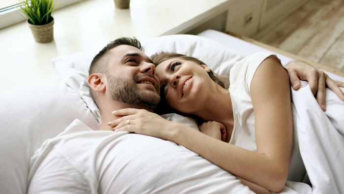 Happy couple relaxing in bed, symbolic of relationships damaged by family feuds.