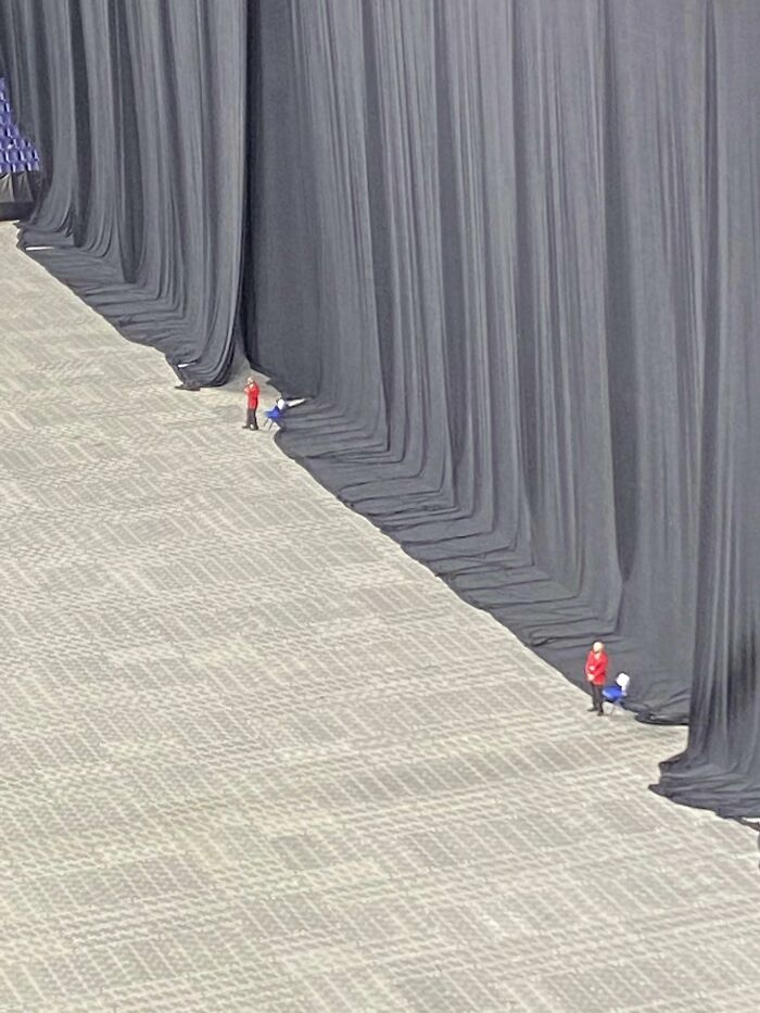 An interesting look at tiny security guards standing in front of massive black stage curtains