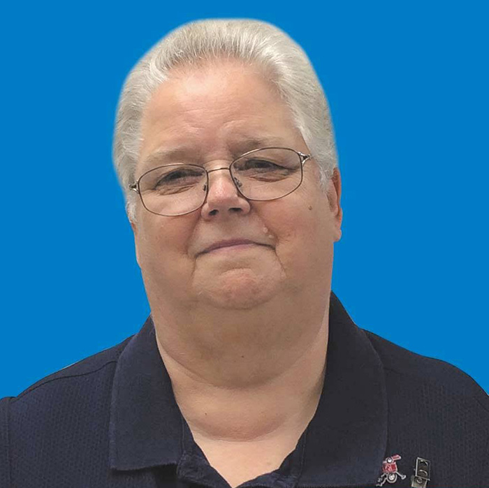 Walmart employee Gayle smiling in a portrait against a blue background Walmart employee Gayle smiling in a portrait against a blue background