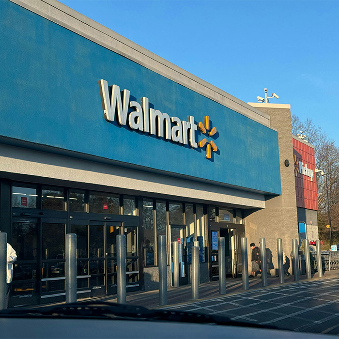 Exterior view of a blue Walmart storefront, representing the workplace of a Walmart employee. Exterior view of a blue Walmart storefront, representing the workplace of a Walmart employee.