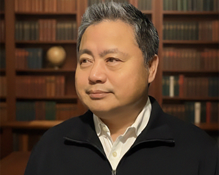 Asian man in a black sweater indoors regarding Kim Jong Un rumor claims. Asian man in a black sweater indoors regarding Kim Jong Un rumor claims.