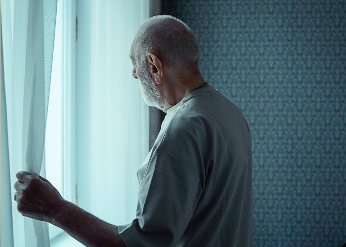 An elderly man looking out a window alone, reflecting warning signs of Lewy Body Dementia. An elderly man looking out a window alone, reflecting warning signs of Lewy Body Dementia.
