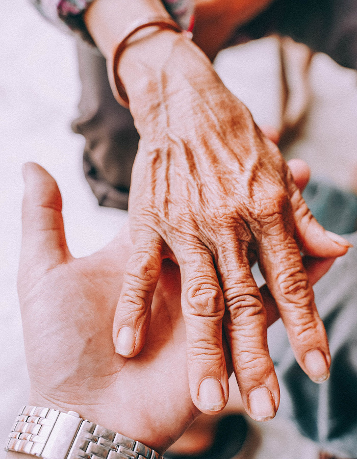 A younger hand gently holding an elderly hand, showing support for Lewy Body Dementia. A younger hand gently holding an elderly hand, showing support for Lewy Body Dementia.