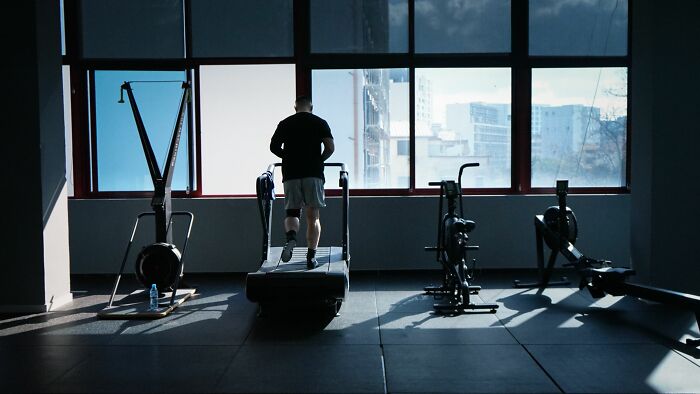 Person exercising on treadmill in gym with large window