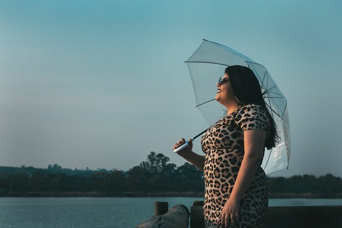 Confident plus-size woman with umbrella enjoying outdoor scenery