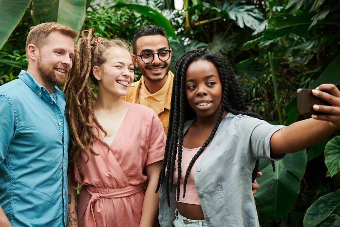 Group of friends smiling taking selfie in tropical garden