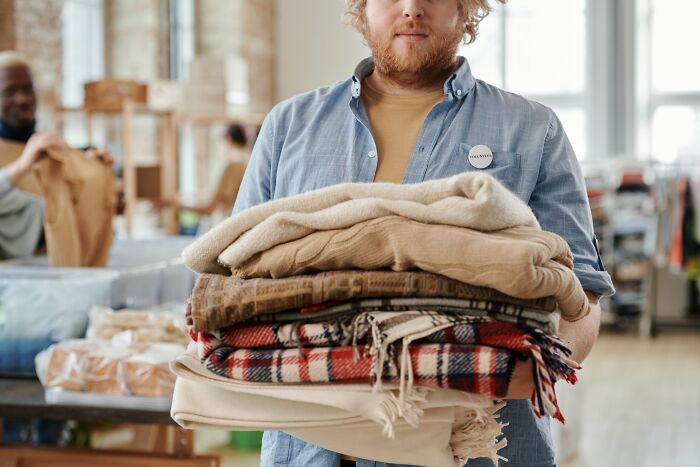 Man holding stack of folded clothes at a donation center