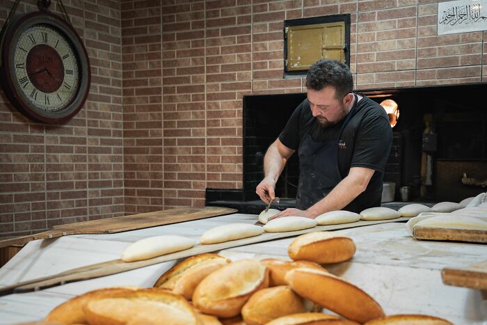 Baker preparing bread in a bakery with fresh loaves, unrelated to weight-related comments