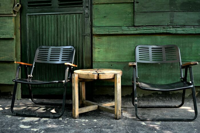 Two empty chairs beside wooden table against green wall