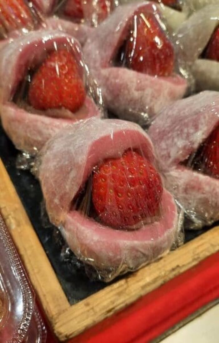 Strawberry mochi desserts looking like mouth-like shapes in a collection of cursed images.