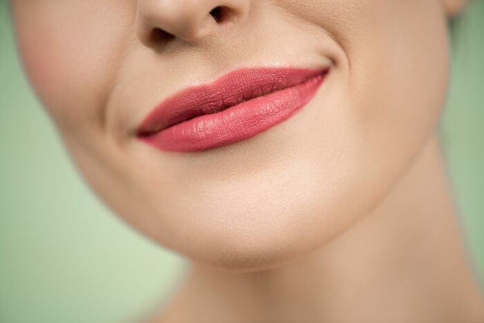 Close-up of a person smiling with pink lipstick showing human body facts about skin and lips.