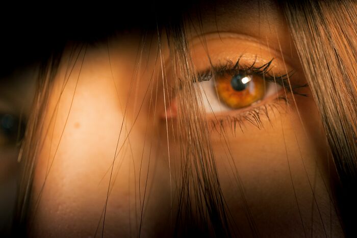Macro photo of a human eye peering through hair representing human body facts