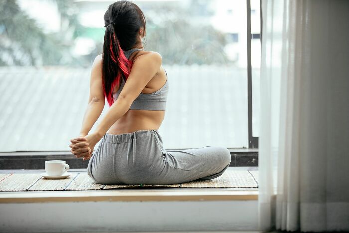 A woman stretching her back on a mat indoors, demonstrating movement and human body facts.
