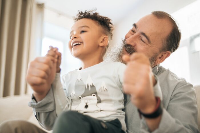A happy young child playing with a smiling older man, illustrating interesting human body facts.