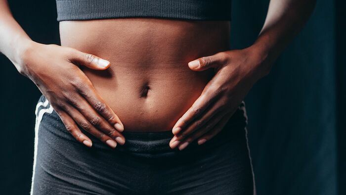 Close up of hands on a person stomach, illustrating human body facts about digestion.