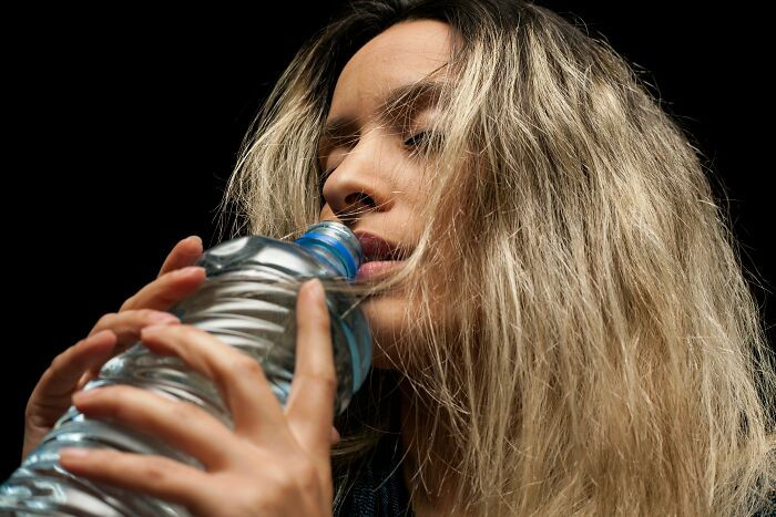 Woman drinking water from a plastic bottle showing human body facts about hydration.