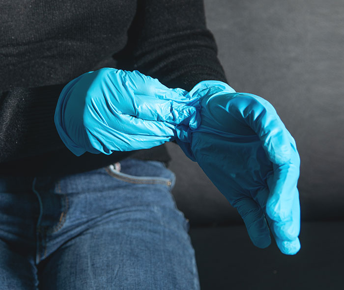 Person putting on blue protective gloves for safety