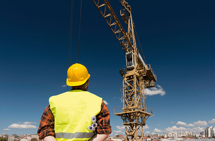 Construction worker in safety gear inspecting crane at worksite