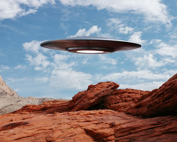 A flying saucer UFO hovering over red rock mountains under blue sky, suggesting strange objects in our skies A flying saucer UFO hovering over red rock mountains under blue sky, suggesting strange objects in our skies