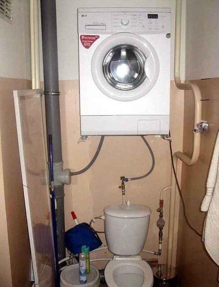 A washing machine mounted dangerously on the wall above a toilet, showcasing an attempt to renovate their homes.