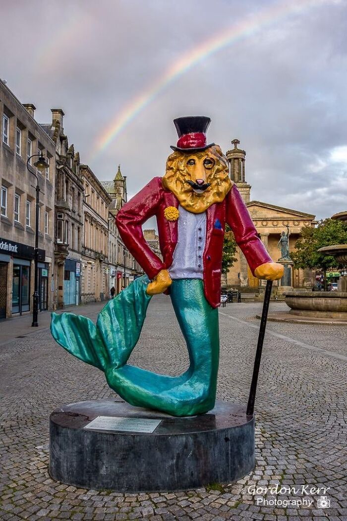 A colorful statue of a dapper lion-headed merman with a cane and top hat, showcasing unique public art