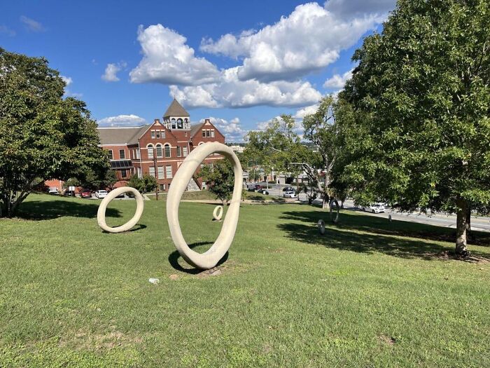 Several circular white rings standing upright in a grassy field on a hill. Bizarre public art example.