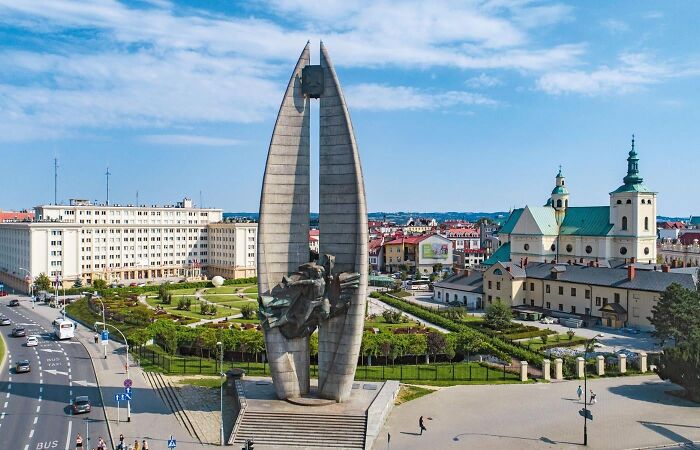 Large modern stone monument rising high above a European city square. Bizarre public art installation.