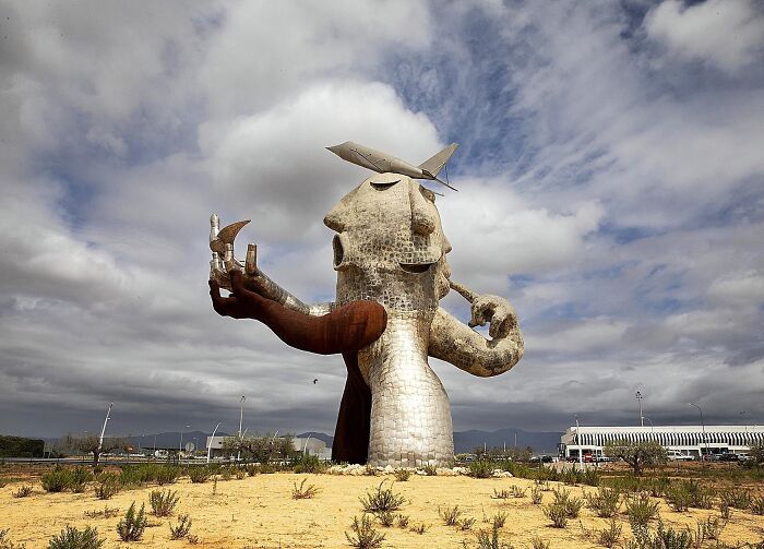 A giant, abstract metallic head statue in a field, a famous and bizarre piece of public art.
