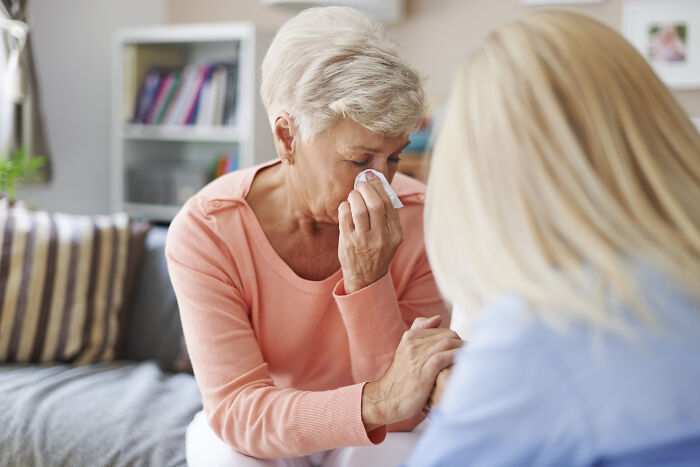 An older woman crying and being comforted, representing emotional family moments