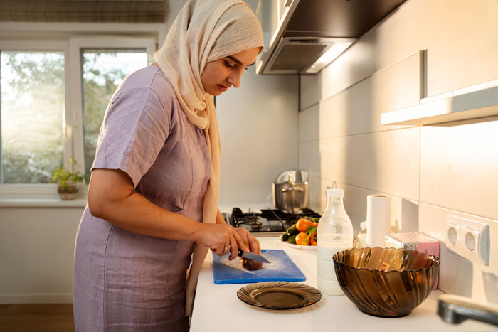 A woman wearing a headscarf prepares cultural cuisine in a home kitchen. A woman wearing a headscarf prepares cultural cuisine in a home kitchen.