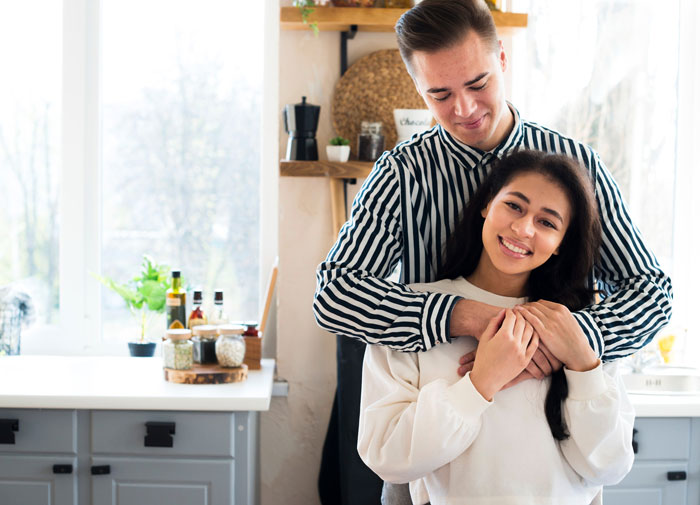 Couple hugging in kitchen, showing relationship dynamic affected by cultural cuisine preferences. Couple hugging in kitchen, showing relationship dynamic affected by cultural cuisine preferences.