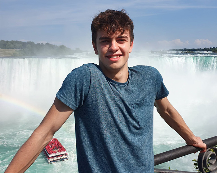Smiling young man posing in front of waterfall Smiling young man posing in front of waterfall