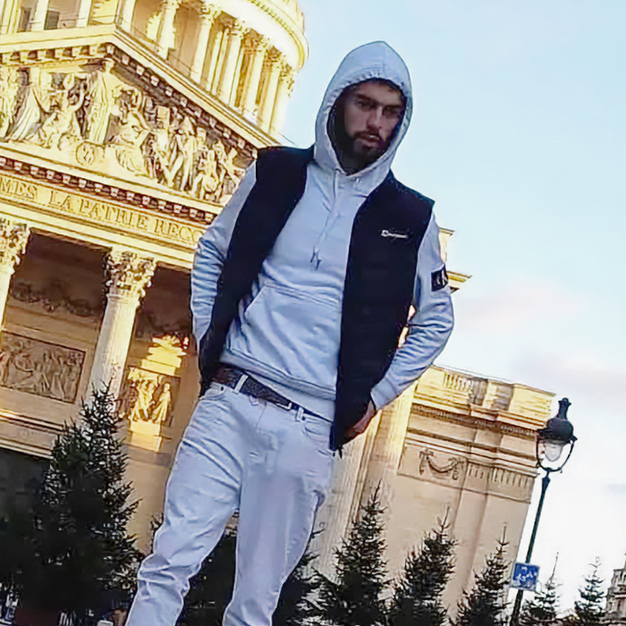 Man wearing hoodie and vest posing near historic building family tiger enclosure Man wearing hoodie and vest posing near historic building family tiger enclosure