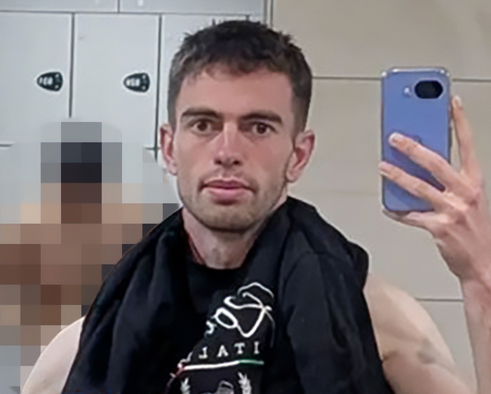Man taking selfie in gym locker room with towel around neck Man taking selfie in gym locker room with towel around neck