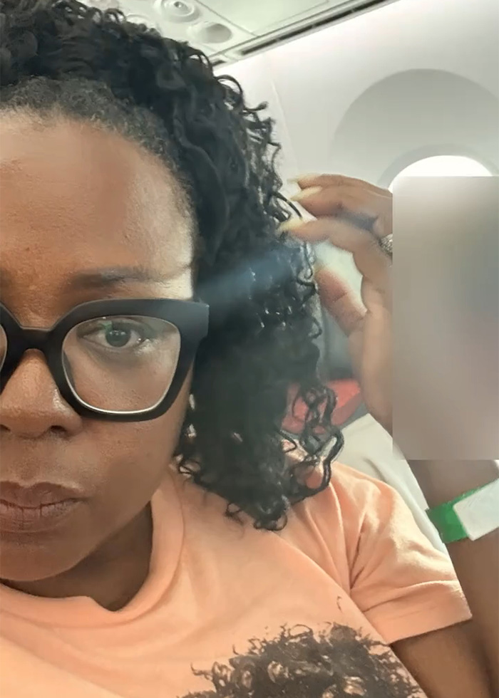 Woman with glasses sitting on plane looking serious
