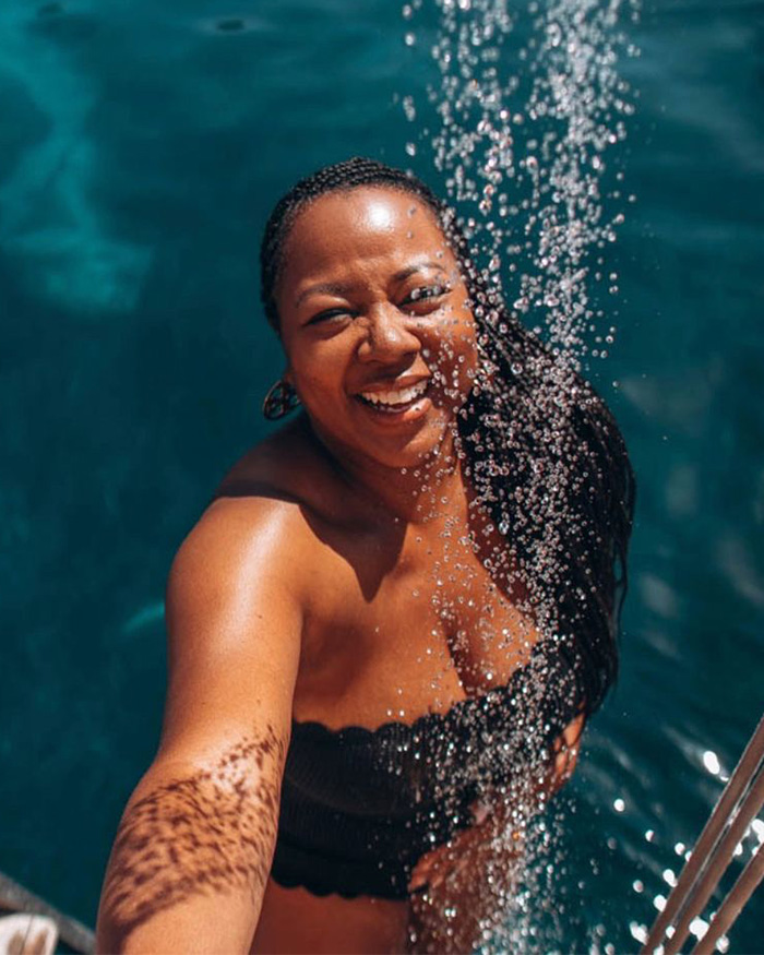 Smiling woman enjoying refreshing water with joyful expression in sunny outdoor setting