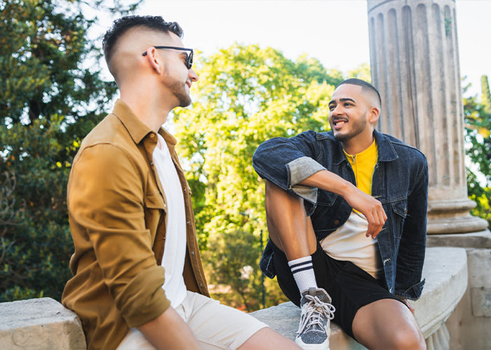 Two young men sitting outdoors talking, reflecting a man who thinks he is getting married in 2 weeks Two young men sitting outdoors talking, reflecting a man who thinks he is getting married in 2 weeks