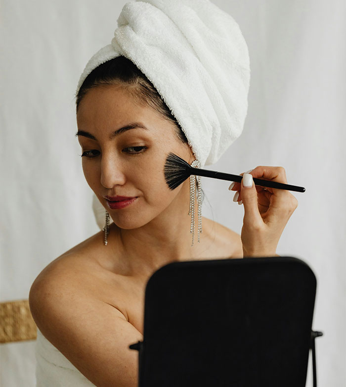 A woman applying makeup, reflecting on beauty trends and lip filler results. A woman applying makeup, reflecting on beauty trends and lip filler results.