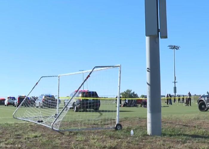 Police and emergency vehicles at a youth soccer field with damaged goal post at accident site Police and emergency vehicles at a youth soccer field with damaged goal post at accident site