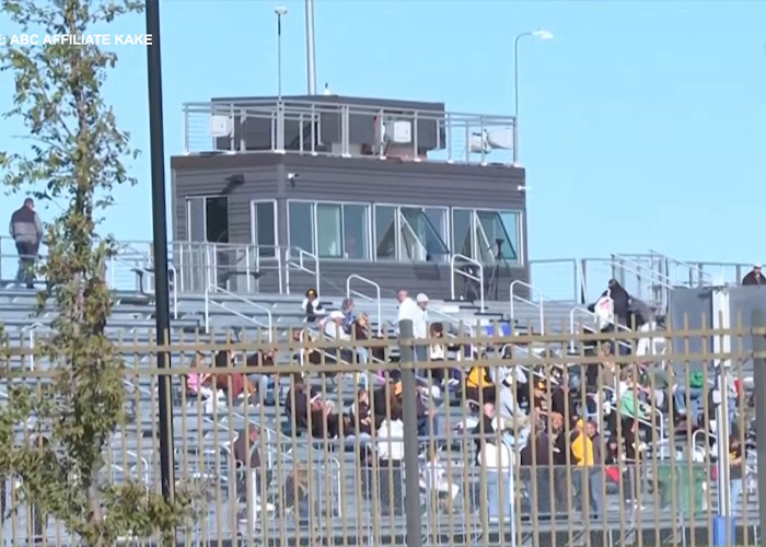 Crowd seated in bleachers watching a youth soccer game on a sunny day Crowd seated in bleachers watching a youth soccer game on a sunny day