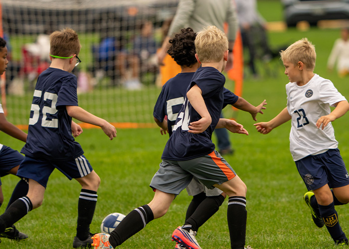 Youth soccer players competing for the ball during a game on a grassy field Youth soccer players competing for the ball during a game on a grassy field