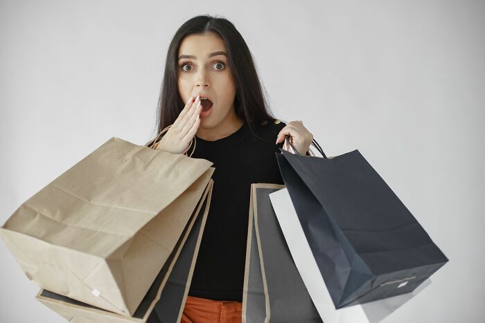 Shocked woman holding several shopping bags, illustrating people behaving like the world owed them everything